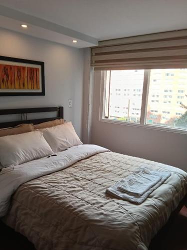 a bedroom with a large bed with a window at Bogotá Urban Suites in Bogotá