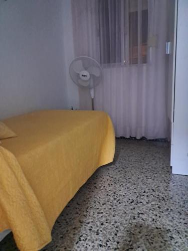 a bedroom with a yellow bed and a fan at Apartamento Tahalia 3 habitaciones in Huelva
