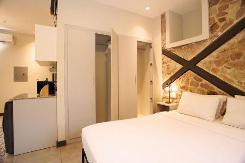 a bedroom with a white bed and a kitchen at AmazINN Places Casa Fortaleza in Panama City