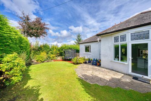 a backyard of a house with a lawn at Group Stay 5BR Home with Parking Sleeps 9 In Giffnock in Giffnock
