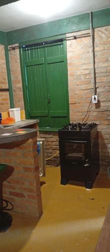 a kitchen with a stove and a green door at Catavento Flats e Suítes in São Sebastião