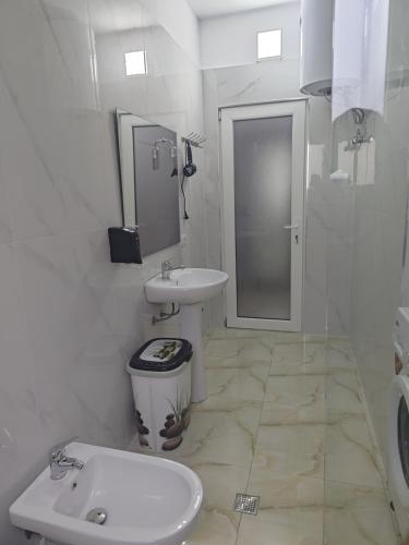 a white bathroom with a sink and a toilet at Prestige Residence Fier in Fier