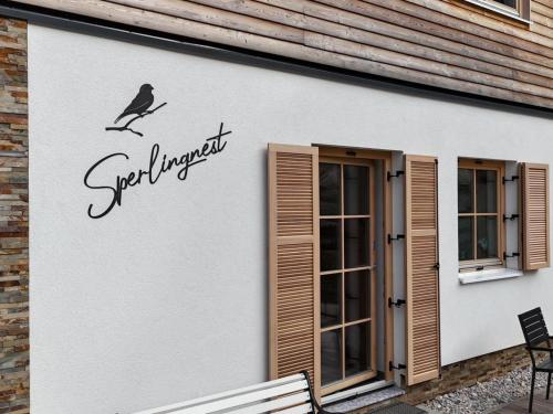a bird on a branch on the side of a building at Sperlingnest in Donnersbachwald
