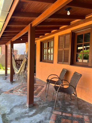 a patio with two chairs and a hammock on a house at Residencial Casa Laranja - Casas na Praia da Ferrugem in Garopaba