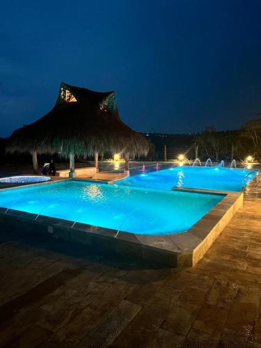 a large swimming pool at night with a straw umbrella at Refugio Ecoturístico Villa Clarita in Estación El Salto