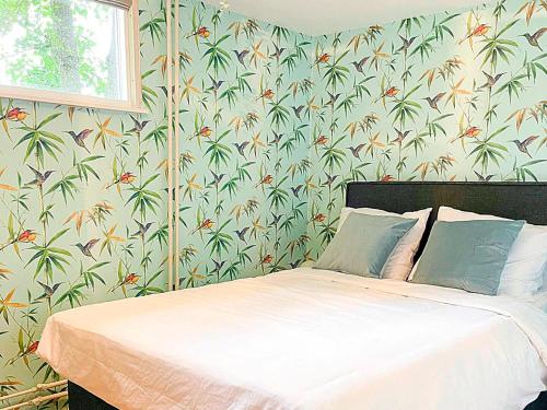a bedroom with a bed with a tropical wallpaper at Kolibrie in Dirkshorn