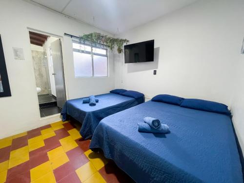 a bedroom with two beds with blue sheets and a window at Coliving Casa encanto, Apartamento - Habitaciones, Laureles-América in Medellín