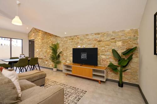 a living room with a tv on a stone wall at AmazINN Places Casa Fortaleza in Panama City