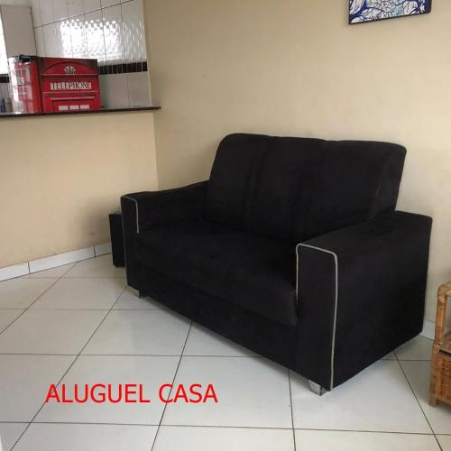 a black couch sitting in a living room at Pousada do Bene - Aluguel Casa in Guarujá
