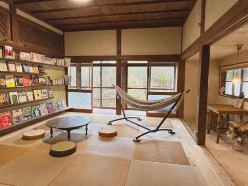 Yamanoにあるその火暮らし Sonohigurashi - Life with Fire Guesthouseのハンモック、テーブル、デスクが備わる客室です。