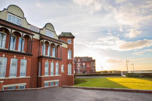 a large brick building with a grass yard in front at Promenade Apartments in Southport