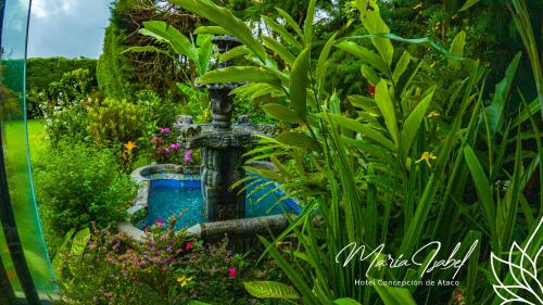 a fountain in a garden with flowers and plants at Hotel María Isabel Ataco in Concepción de Ataco
