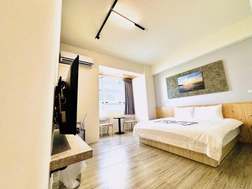 a bedroom with a bed and a desk and a television at 看海季節&聽海約定精緻旅店 in Magong