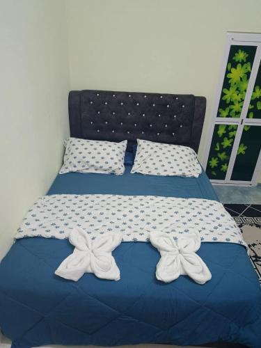 a bed with two white bows on top of it at Ameera family homestay in Bachok