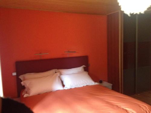 a bed with orange walls and white pillows at Beluga in La Godivelle