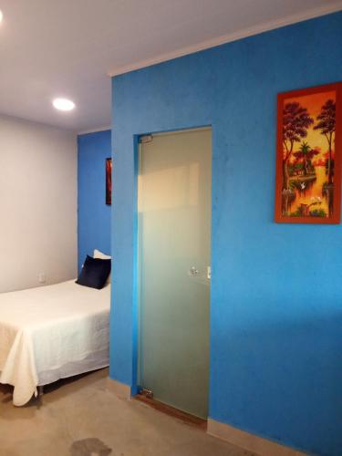 a room with a blue wall with a bed and a door at Chalé Pôr do Sol II in Alto Paraíso de Goiás