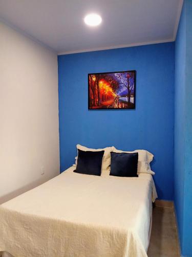 a bedroom with a bed with a blue wall at Chalé Pôr do Sol II in Alto Paraíso de Goiás