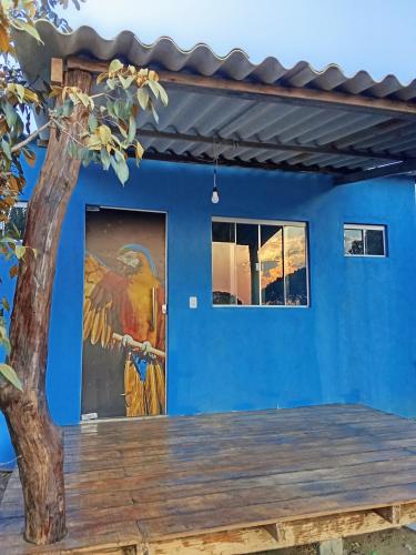 a blue wall with a painting of a parrot on it at Chalé Pôr do Sol II in Alto Paraíso de Goiás