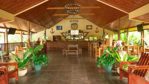 a restaurant with wooden tables and chairs and plants at La Cuna Inn in Puerto Jiménez