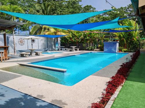 a swimming pool in a resort with blue umbrellas at La Cuna Inn in Puerto Jiménez