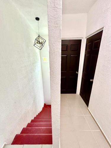 a stairway with a red carpet and a black door at Sumergete Nueva Residencia en Playa del Carmen in Playa del Carmen