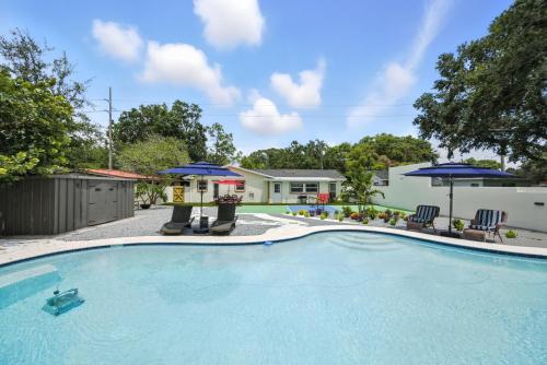 a swimming pool with two chairs and umbrellas at Luxury Oasis Retreat Pickleball Pool Spa Billiard Gaming in Tampa