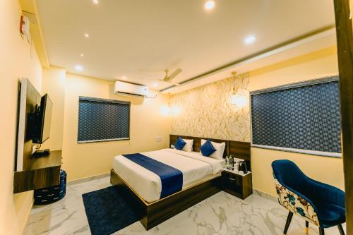 a bedroom with a bed and a tv and a chair at Livotel Premium Hotel in Bhubaneshwar