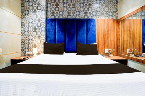 a bedroom with a large white bed with blue curtains at Hotel O Shiv Sai Residency Lodging & Boarding in Bapane