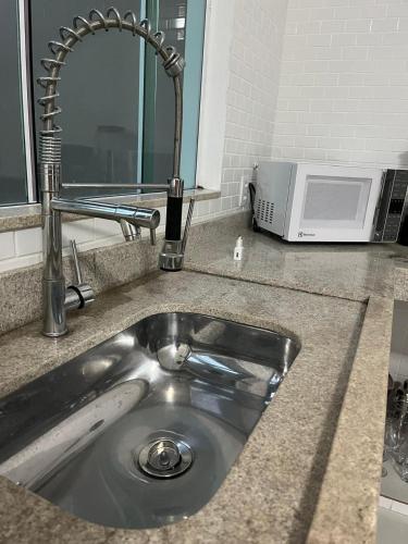 a kitchen counter with a sink and a microwave at Apartamento Paraiso Búzios l in Búzios