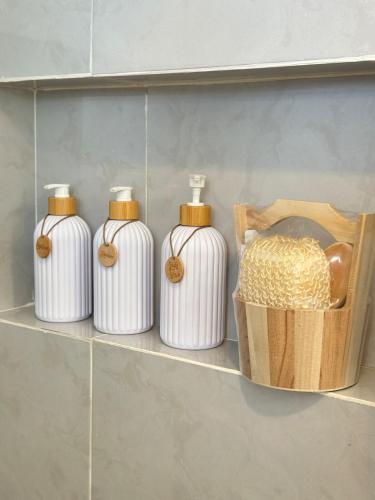 four white bottles on a shelf next to a basket at Captain CLIFFs House in Pilar