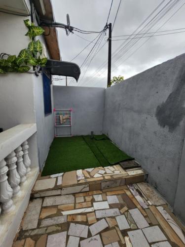 ein kleiner Innenhof mit einem grünen Rasen an einer Wand in der Unterkunft CRYSTAL Azur Gabon in Libreville