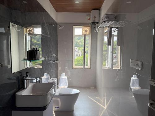a bathroom with a sink and a toilet and windows at 3BR Abode with Plunge Pool and Monsoon place view in Udaipur