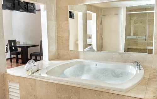 a large bath tub in a bathroom with a mirror at Auto Posada Bombay in Cancún