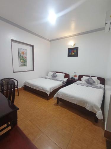 a bedroom with two beds and a table and a desk at Du Hung 2 Hotel in Ha Tien