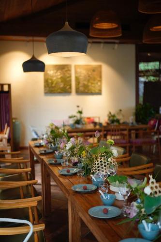 a long wooden table with plates and flowers on it at The Apsara Lodge-Airport or TS Free pick-up over 3 nights in Yangshuo