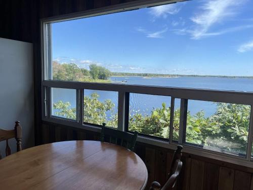 une table et des chaises dans une pièce avec une grande fenêtre dans l'établissement 2-bedroom Waterfront Cottage in Georgian Bay - Rockwood #7, à Dillon