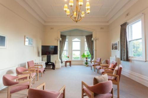 a waiting room with chairs and a tv and a chandelier at Mary MacKillop Spirituality Centre, St Joseph's by the sea in Williamstown