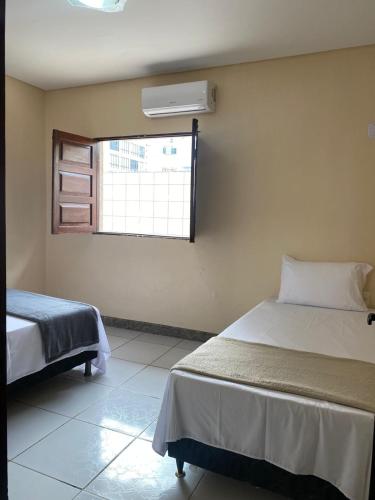 a bedroom with two beds and a window at Casa Porto in Porto De Galinhas
