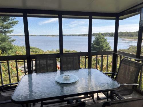 une table sur une véranda grillagée avec vue sur l'eau dans l'établissement 3-bedroom Cottage in Georgian Bay - Rockwood #10, à Dillon