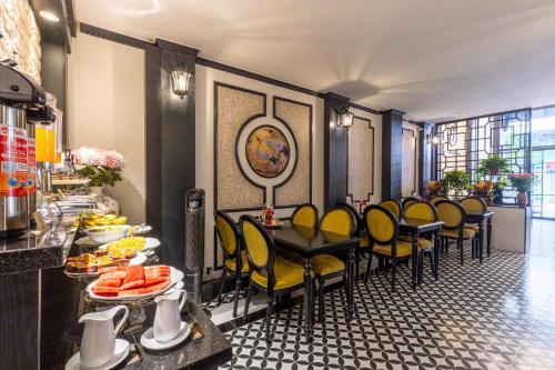 a restaurant with yellow chairs and a table with food at Hanoi House Hotel & Travel in Hanoi