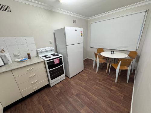 a kitchen with a white refrigerator and a table at 1 Turf St Workers Accommodation in Grafton