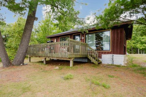 a small house with a large deck next to a tree at 2-Bedroom Cottage #2 - Sand Bay in Dillon