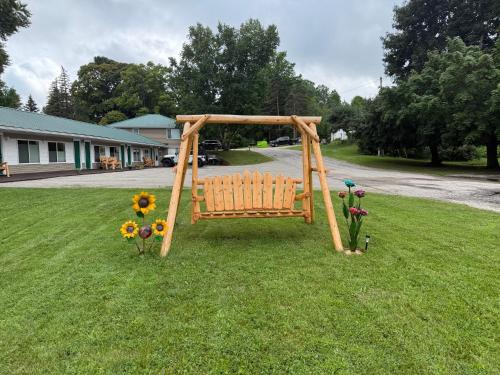a wooden swing in the grass with flowers at Eddys Motel in East Jordan