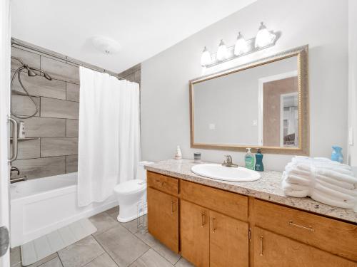 une salle de bain avec un lavabo, une baignoire et un miroir dans l'établissement The Splash & Stay Villa, à Belle River