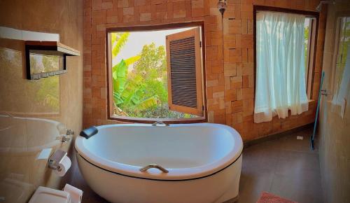 una bañera en un baño con ventana en Vila Kuir Hospedagens, en Alto Paraíso de Goiás