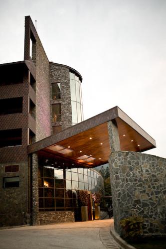 a large building with a stone wall in front of it at Lux Garden Hotel in Azuga