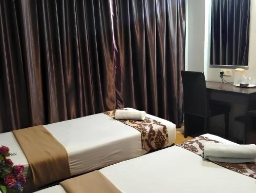 a room with two beds and a desk with a computer at Hotel Sayang in Kulai