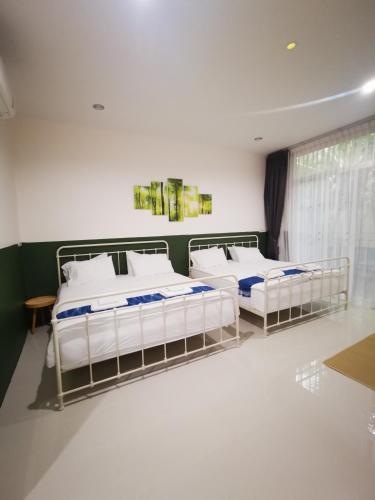 two beds in a room with white walls at บุญเมืองน่าน in Nan