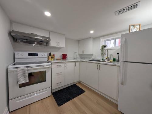 a kitchen with white cabinets and a white refrigerator at The Urban Hideaway - Stylish Stay - Prime Spot in Hamilton