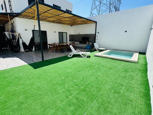 a patio with green grass and a swimming pool at Sumergete y Relajate, Nueva Residencia en Mérida in Mérida